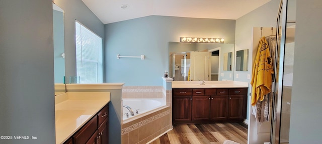 1691 Canopy Oaks Dr, Orange Park, FL 32065 - bathroom with two vanities, vaulted ceiling, a stall shower, a bath, and wood finished floors