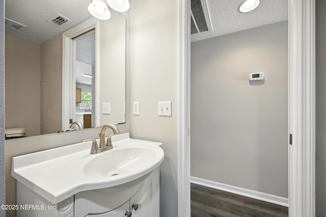 172 King Arthur Ct, Saint Augustine, FL 32086 - bathroom with vanity, wood finished floors, a textured ceiling, and baseboards