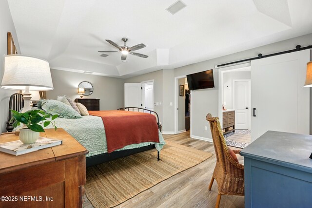 309 Elza Ln, Saint Augustine, FL 32086 - bedroom featuring a raised ceiling, light wood finished floors, a barn door, baseboards, and ceiling fan