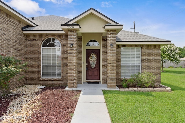 2000 Belhaven Dr, Orange Park, FL 32065 - view of exterior entry featuring roof with shingles, brick siding, and a lawn