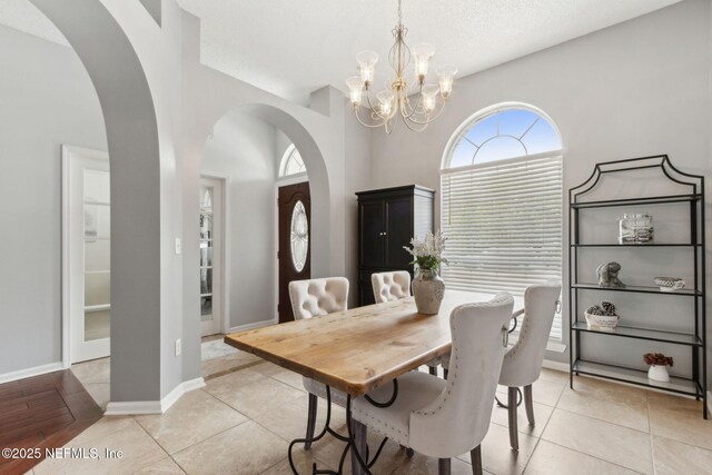 2000 Belhaven Dr, Orange Park, FL 32065 - dining area featuring a chandelier, arched walkways, baseboards, and light tile patterned floors