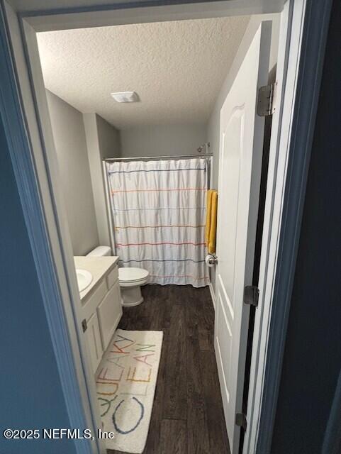 2358 Evening Oaks Ln, Green Cove Springs, FL 32043 - bathroom featuring vanity, wood finished floors, toilet, curtained shower, and a textured ceiling