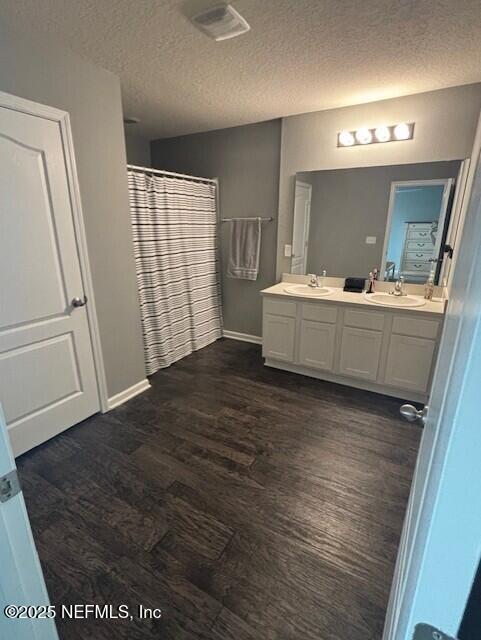 2358 Evening Oaks Ln, Green Cove Springs, FL 32043 - full bath with wood finished floors, double vanity, baseboards, a textured ceiling, and a shower with shower curtain