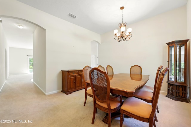 372 Johns Creek Pkwy, Saint Augustine, FL 32092 - dining space with arched walkways, a chandelier, light carpet, and baseboards
