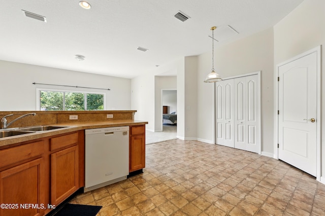 372 Johns Creek Pkwy, Saint Augustine, FL 32092 - kitchen with dishwasher, a sink, brown cabinets, light stone finish flooring, and hanging light fixtures