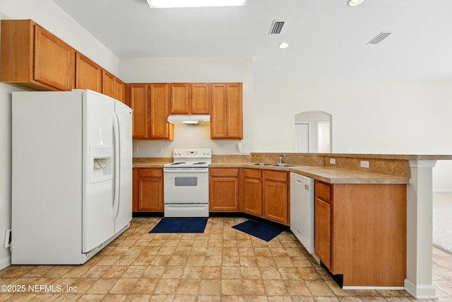 372 Johns Creek Pkwy, Saint Augustine, FL 32092 - kitchen featuring white appliances, a peninsula, arched walkways, a sink, and light stone finish flooring