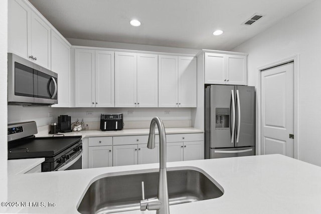 712 Cherry Elm Dr, Saint Augustine, FL 32092 - kitchen with stainless steel appliances, a sink, light countertops, white cabinets, and recessed lighting