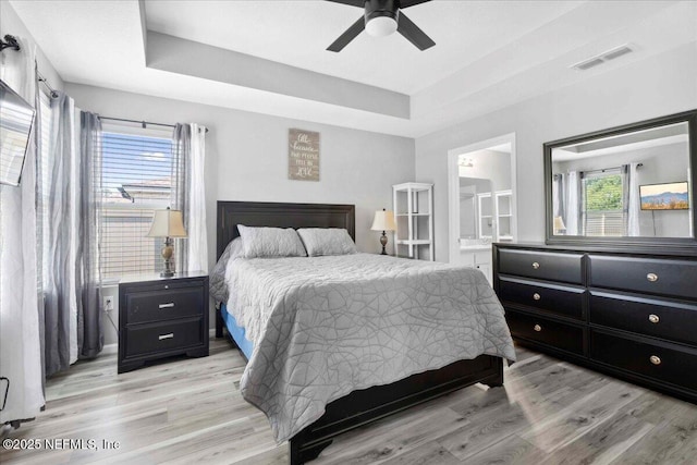 86815 Iron Rail Ct, Yulee, FL 32097 - bedroom with a tray ceiling, multiple windows, and light wood-style flooring