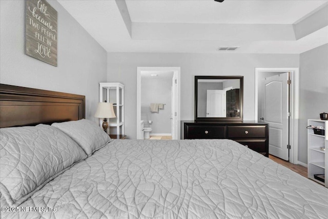 86815 Iron Rail Ct, Yulee, FL 32097 - bedroom with a tray ceiling, connected bathroom, and wood finished floors