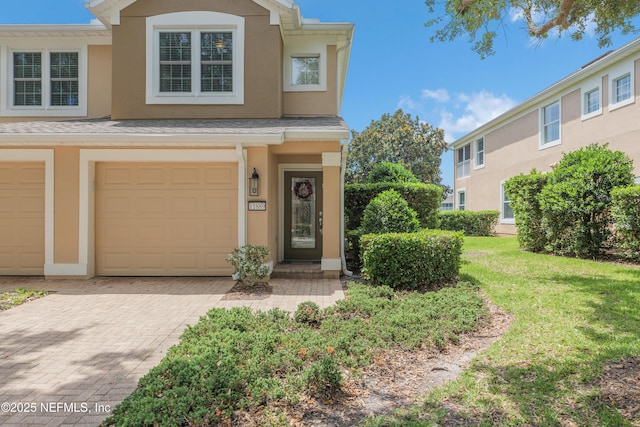 11889 Surfbird Cir Unit 10F, Jacksonville, FL 32256 - view of front of home with stucco siding, an attached garage, decorative driveway, and a front yard