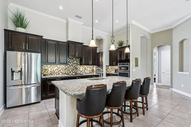 33 Tinker Ct, Fruit Cove, FL 32259 - kitchen featuring appliances with stainless steel finishes, arched walkways, a sink, light tile patterned flooring, and ornamental molding