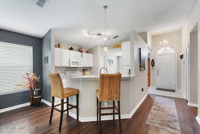 589 Prosperity Lake Dr, Saint Augustine, FL 32092 - kitchen featuring white microwave, a breakfast bar, dark wood-style floors, white cabinetry, and lofted ceiling