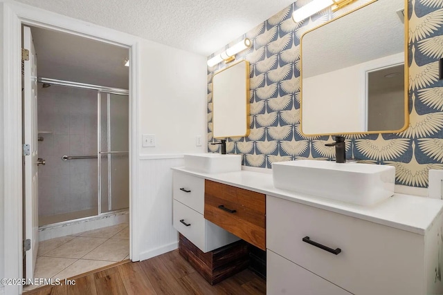 12 Flagler Blvd Unit A203, Saint Augustine, FL 32080 - full bathroom featuring double vanity, a stall shower, a textured ceiling, wainscoting, and wood finished floors