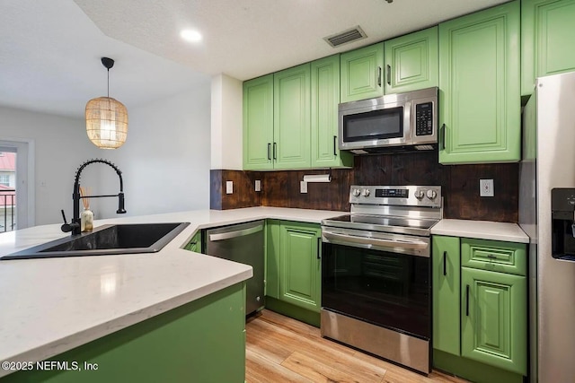 12 Flagler Blvd Unit A203, Saint Augustine, FL 32080 - kitchen featuring stainless steel appliances, a sink, green cabinetry, light wood-style floors, and decorative light fixtures