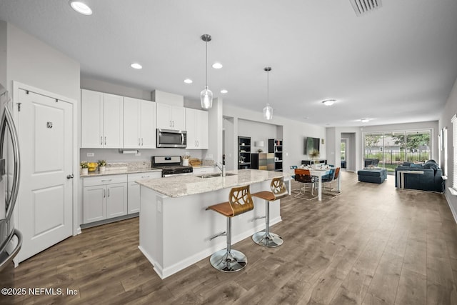149 Ferndale Way, Saint Augustine, FL 32092 - kitchen featuring stainless steel appliances, open floor plan, dark wood finished floors, a kitchen bar, and white cabinetry