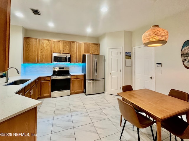 12301 Kernan Forest Blvd Unit 1905, Jacksonville, FL 32225 - kitchen featuring stainless steel appliances, a sink, brown cabinets, light countertops, and decorative light fixtures