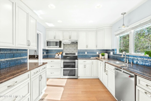 415 Seminole Rd, Atlantic Beach, FL 32233 - kitchen with stainless steel appliances, under cabinet range hood, white cabinetry, a sink, and backsplash