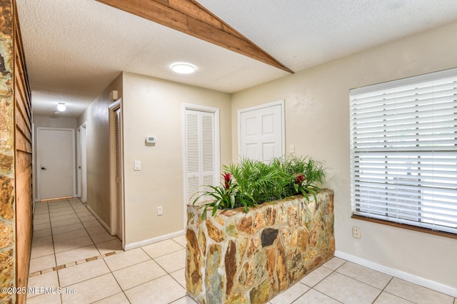 122 Raintree Woods Trl, Palatka, FL 32177 - corridor with a textured ceiling, light tile patterned floors, vaulted ceiling, and baseboards