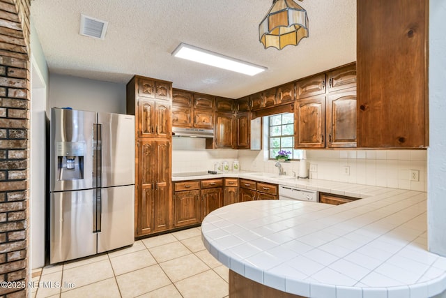 122 Raintree Woods Trl, Palatka, FL 32177 - kitchen featuring stainless steel fridge, tile countertops, under cabinet range hood, white dishwasher, and a textured ceiling