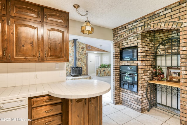 122 Raintree Woods Trl, Palatka, FL 32177 - kitchen featuring a wood stove, tile countertops, oven, light tile patterned flooring, and a textured ceiling
