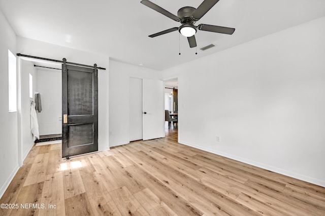 822 Valnera Ct, Saint Augustine, FL 32086 - unfurnished bedroom featuring a barn door, wood finished floors, baseboards, and a ceiling fan