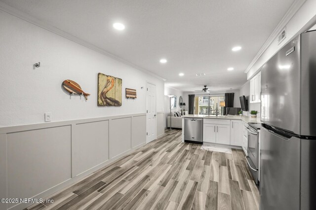 5811 Atlantic Blvd Unit 153, Jacksonville, FL 32207 - kitchen featuring stainless steel appliances, open floor plan, a peninsula, ornamental molding, and white cabinetry