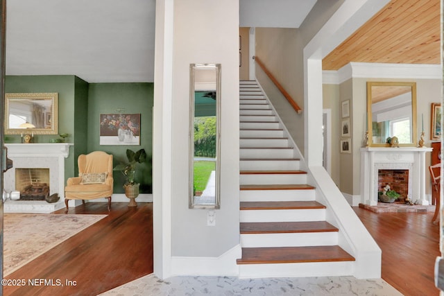 7265 Beach Rd, Elkton, FL 32033 - staircase featuring a fireplace with raised hearth, wood finished floors, baseboards, and crown molding