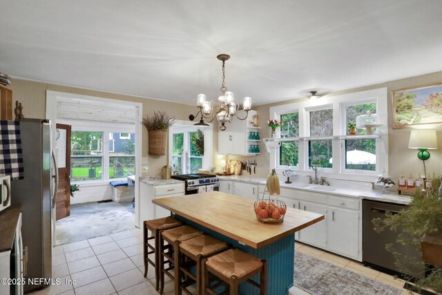 7265 Beach Rd, Elkton, FL 32033 - kitchen with wood counters, a sink, stainless steel appliances, light tile patterned floors, and white cabinetry
