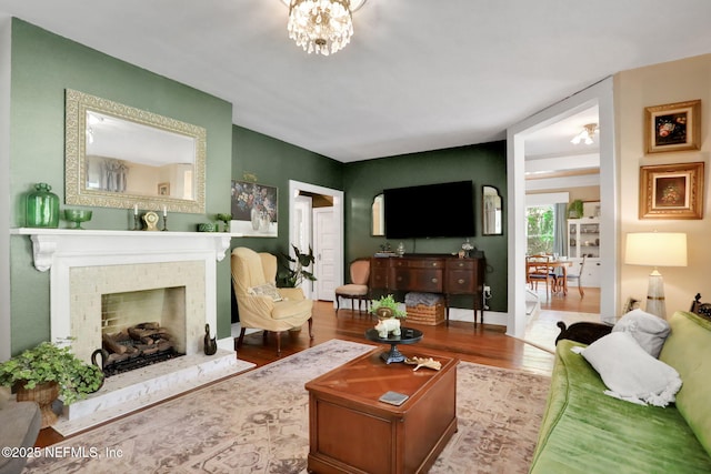 7265 Beach Rd, Elkton, FL 32033 - living area featuring wood finished floors, a fireplace, a chandelier, and baseboards