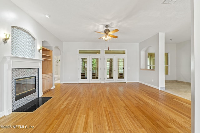 2305 Range Crescent Ct, Fleming Island, FL 32003 - unfurnished living room with a ceiling fan, a tiled fireplace, light wood-type flooring, and baseboards