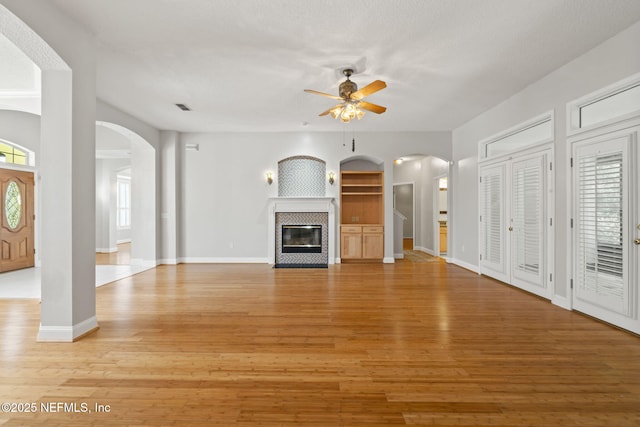 2305 Range Crescent Ct, Fleming Island, FL 32003 - unfurnished living room with arched walkways, a ceiling fan, light wood-style flooring, and a fireplace