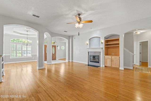 2305 Range Crescent Ct, Fleming Island, FL 32003 - unfurnished living room with ceiling fan, light wood-type flooring, a tile fireplace, a textured ceiling, and arched walkways