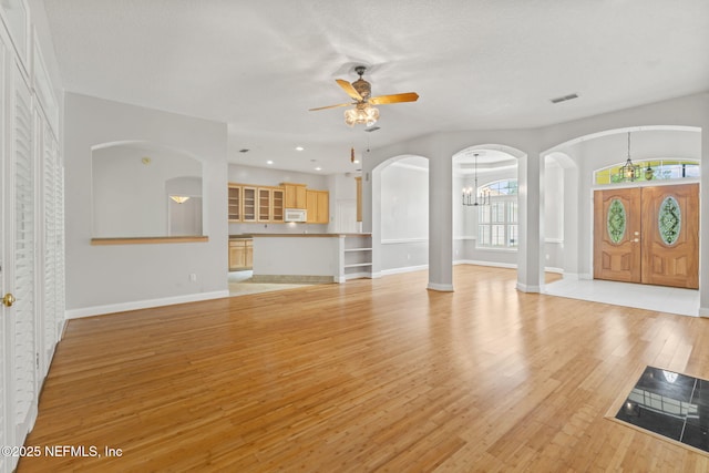 2305 Range Crescent Ct, Fleming Island, FL 32003 - unfurnished living room with ceiling fan, light wood-style flooring, baseboards, a chandelier, and arched walkways