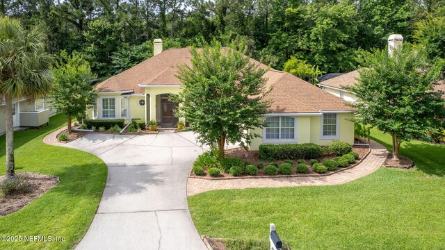 2305 Range Crescent Ct, Fleming Island, FL 32003 - mediterranean / spanish house featuring a front lawn, stucco siding, roof with shingles, concrete driveway, and a chimney