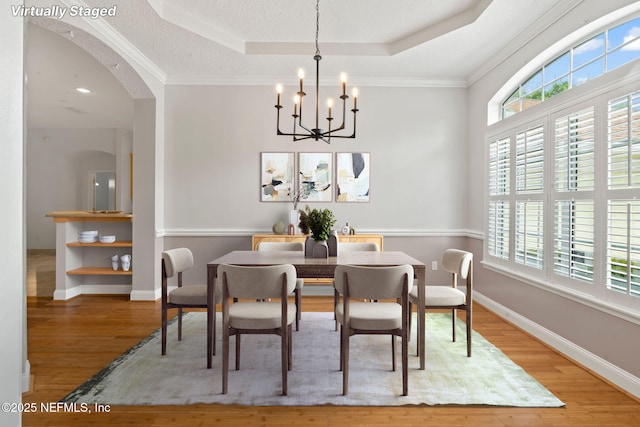 2305 Range Crescent Ct, Fleming Island, FL 32003 - dining space featuring a tray ceiling, wood finished floors, a chandelier, arched walkways, and crown molding