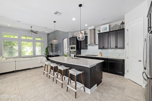 80 Atlas Dr, Saint Augustine, FL 32092 - kitchen featuring wall chimney range hood, stainless steel appliances, open floor plan, arched walkways, and a sink
