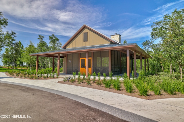 80 Atlas Dr, Saint Augustine, FL 32092 - country-style home with a chimney, board and batten siding, a sunroom, and a standing seam roof