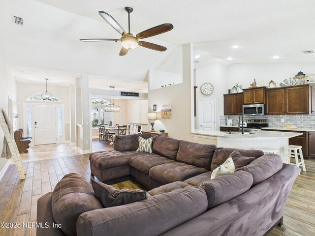 88137 Maybourne Rd, Yulee, FL 32097 - living area with light wood-style flooring, ceiling fan, high vaulted ceiling, a chandelier, and baseboards