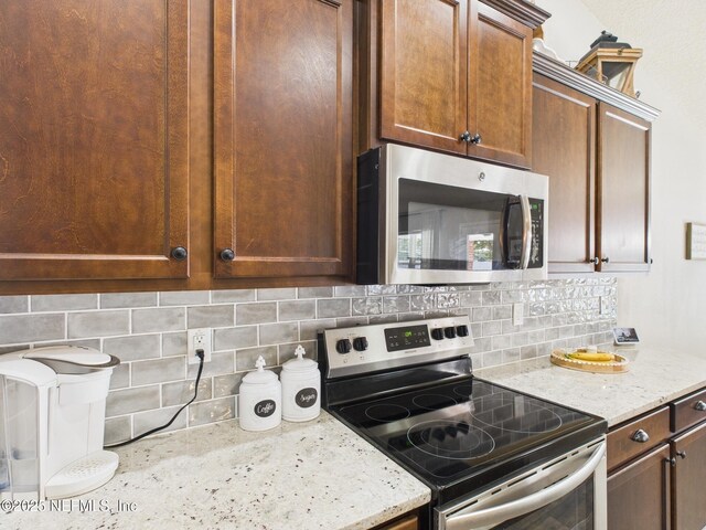 88137 Maybourne Rd, Yulee, FL 32097 - kitchen featuring appliances with stainless steel finishes, decorative backsplash, and light stone countertops