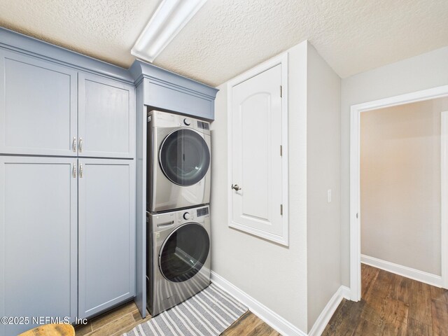 88137 Maybourne Rd, Yulee, FL 32097 - laundry area featuring estacked washer and dryer, cabinet space, dark wood-style flooring, baseboards, and a textured ceiling