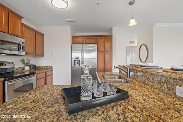 104 Laguna Villas Blvd Unit F33, Jacksonville Beach, FL 32250 - kitchen featuring stainless steel appliances, a sink, dark stone countertops, brown cabinets, and pendant lighting