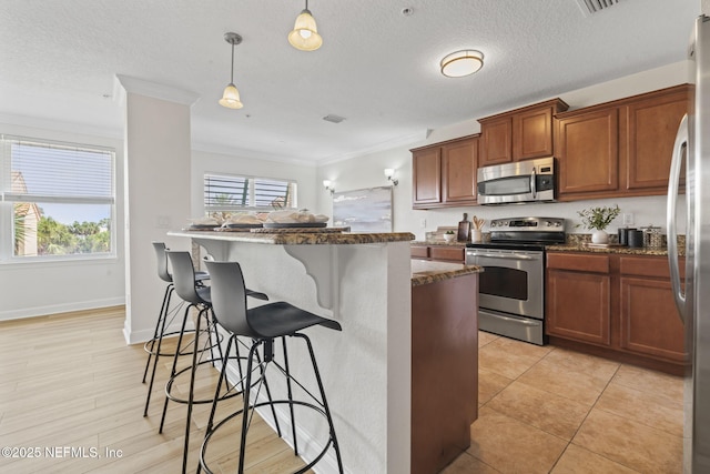 104 Laguna Villas Blvd Unit F33, Jacksonville Beach, FL 32250 - kitchen featuring appliances with stainless steel finishes, a kitchen bar, ornamental molding, dark stone countertops, and brown cabinets