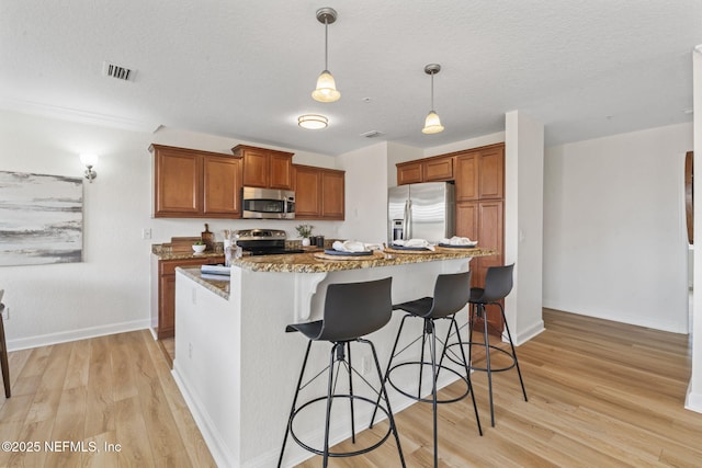 104 Laguna Villas Blvd Unit F33, Jacksonville Beach, FL 32250 - kitchen featuring stainless steel appliances, light wood finished floors, a breakfast bar, brown cabinets, and stone counters