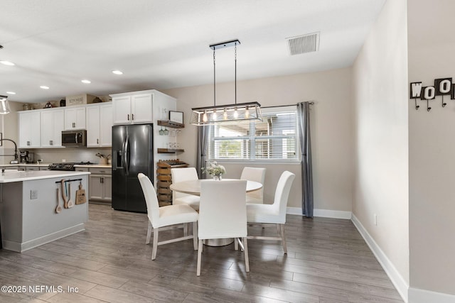 212 Foxcross Ave, Saint Johns, FL 32092 - kitchen featuring appliances with stainless steel finishes, light countertops, wood finished floors, white cabinetry, and decorative light fixtures