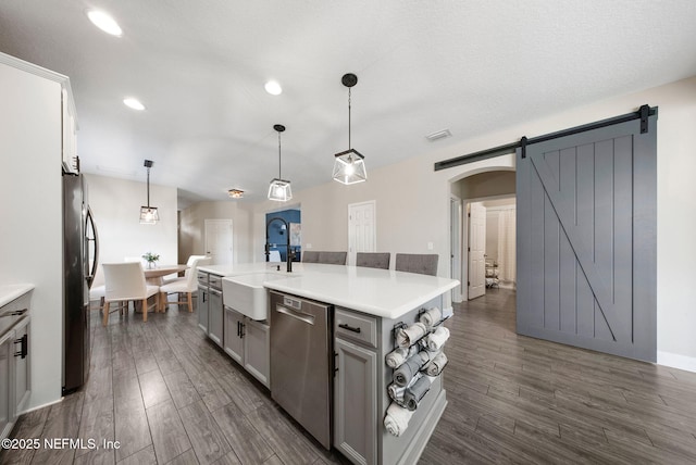 212 Foxcross Ave, Saint Johns, FL 32092 - kitchen featuring appliances with stainless steel finishes, a barn door, gray cabinets, arched walkways, and dark wood-style floors