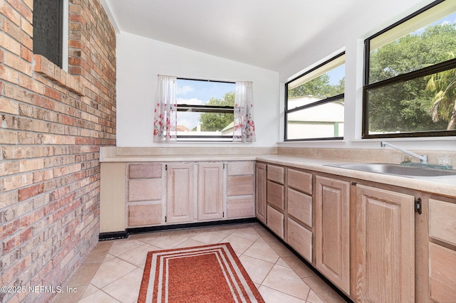 12373 Shell Beach Trl, Jacksonville, FL 32246 - kitchen with lofted ceiling, light countertops, light brown cabinetry, light tile patterned floors, and brick wall