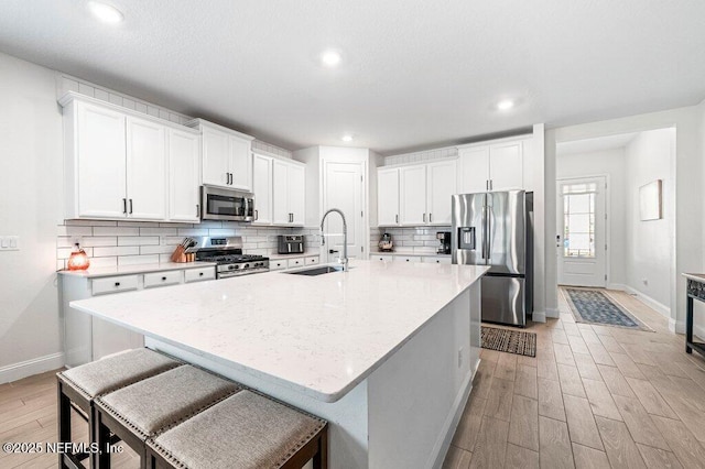 154 Pine Candle Way, Saint Augustine, FL 32092 - kitchen with appliances with stainless steel finishes, a sink, baseboards, light wood-style flooring, and decorative backsplash