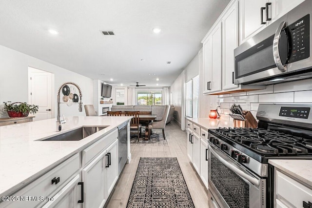 154 Pine Candle Way, Saint Augustine, FL 32092 - kitchen with stainless steel appliances, a sink, white cabinetry, light wood-type flooring, and recessed lighting