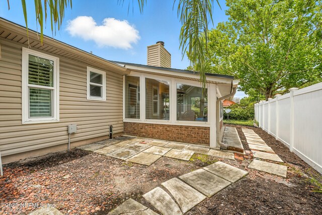11019 Crumpet Ct, Jacksonville, FL 32257 - back of property with a chimney, a sunroom, a patio area, and brick siding