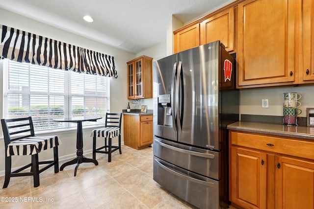 3724 Windmaker Way, Jacksonville, FL 32224 - kitchen with stainless steel refrigerator with ice dispenser, dark countertops, brown cabinets, glass insert cabinets, and recessed lighting